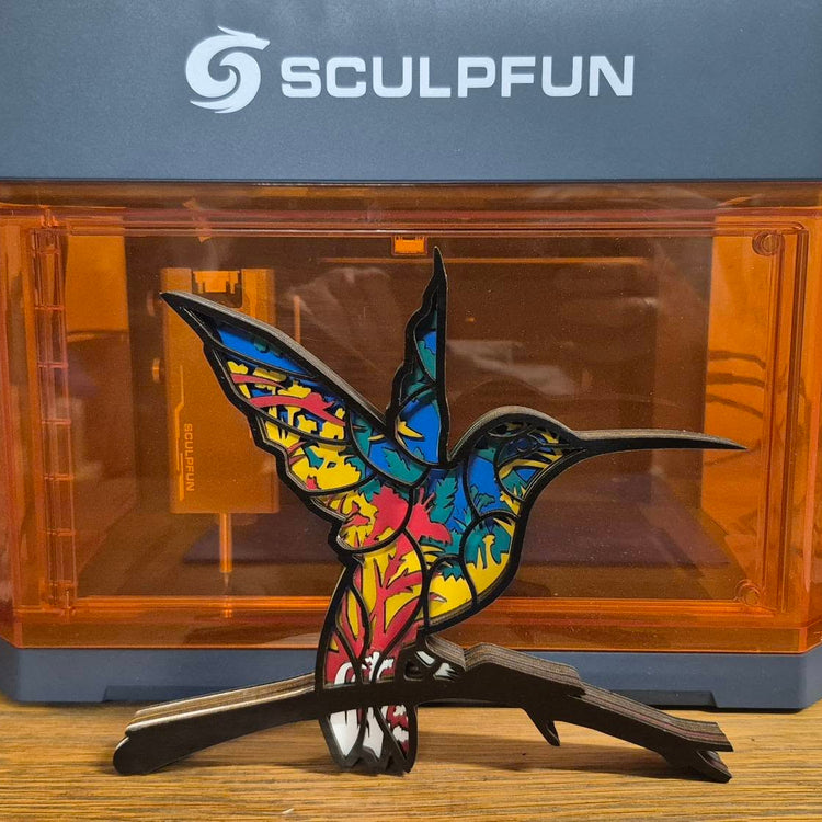 Colorful hummingbird sculpture displayed with the Sculpfun iCube Ultra laser machine