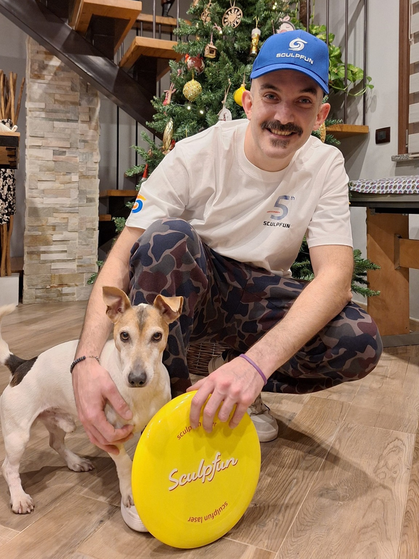 Laser Kastell and his dog with a personalized yellow disc, laser engraved with Sculpfun text, in a room decorated with a Christmas tree