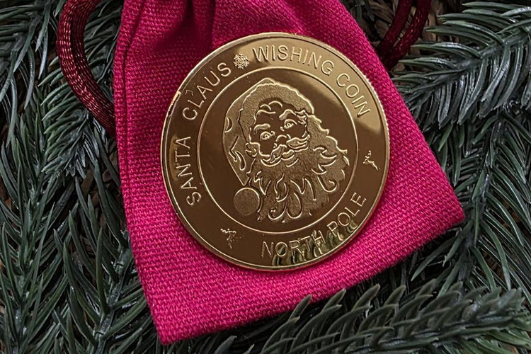 Custom Santa Claus gold coin laser engraved by Sculpfun, displayed on pink fabric among festive greenery