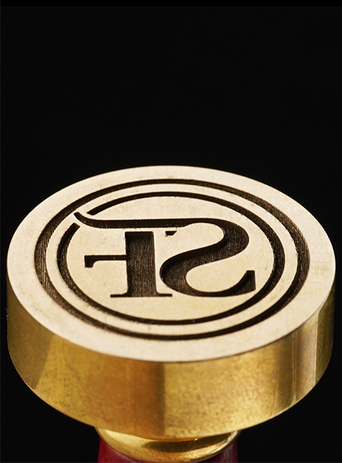 Gold-colored seal with a logo engraved by A9 Ultra fiber laser on a black background